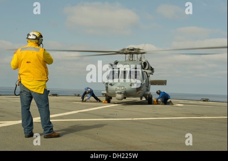 Als Military Sealift Command Staatsdienst Seemann signalisiert den Piloten eines MH-60 Seahawk-Hubschrauber auf dem Flugdeck der US 6. Flotte Flaggschiff USS Mount Whitney (LCC-20). Mount Whitney, Haus-portiert in Gaeta, Italien, führt im Gange maritim Stockfoto