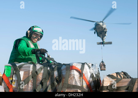Golf von OMAN (23. Oktober 2013)-Logistik-Spezialist 3. Klasse Amber Munoz entfernt ein Gepäcknetz aus einer Palette von Lieferungen während ein MH-60 s Sea Hawk Hubschrauber zugewiesen, die staubigen Hunde der Hubschrauber Meer bekämpfen Squadron (HSC) 7 Lieferungen zum Flug de senkt Stockfoto