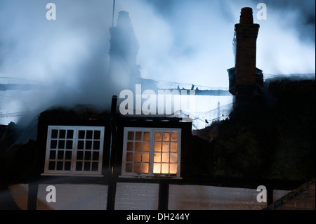 Reetdachhaus-Dach auf Feuer in der Nacht Stockfoto