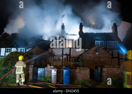 Reetdachhaus-Dach auf Feuer in der Nacht Stockfoto