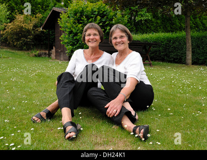 Zwei rüstige Zwillingsschwestern im Garten zu sitzen Stockfoto