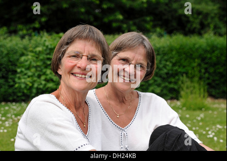 Zwei rüstige Zwillingsschwestern im Garten zu sitzen Stockfoto