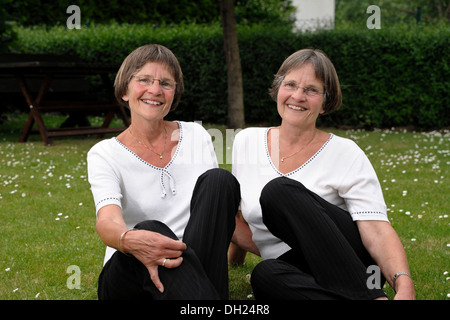 Zwei rüstige Zwillingsschwestern im Garten zu sitzen Stockfoto