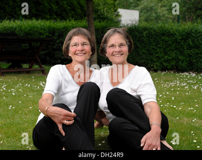 Zwei rüstige Zwillingsschwestern im Garten zu sitzen Stockfoto