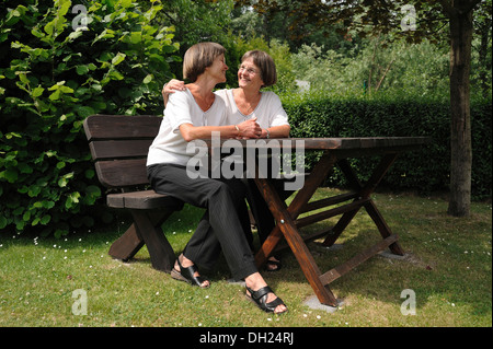 Zwei rüstige Zwillingsschwestern sitzen auf einer Bank Stockfoto