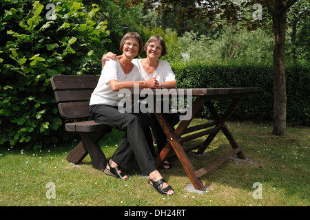 Zwei rüstige Zwillingsschwestern sitzen auf einer Bank Stockfoto