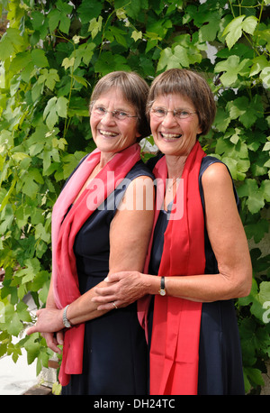 Zwei rüstige Zwillingsschwestern gekleidet gleichermaßen und tragen rote Schals Stockfoto