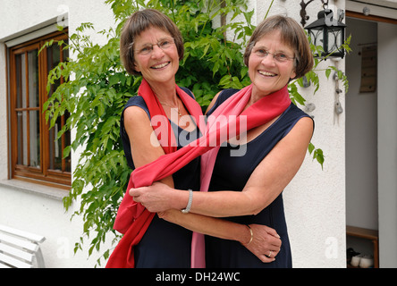 Zwei rüstige Zwillingsschwestern gekleidet gleichermaßen und tragen rote Schals Stockfoto