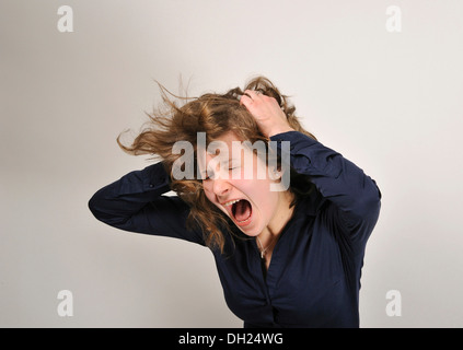 Junge Frau, 20, wütend, hält schreit, ihre Hände auf ihren Kopf und an den Haaren reißen Stockfoto