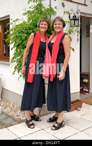 Zwei rüstige Zwillingsschwestern gekleidet gleichermaßen und tragen rote Schals Stockfoto