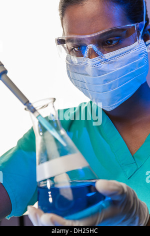Asiatische medizinische oder wissenschaftliche Forscherin oder Arzt mit Hilfe einer Pipette & konischen Kolben blaue Lösung in einem Labor Stockfoto