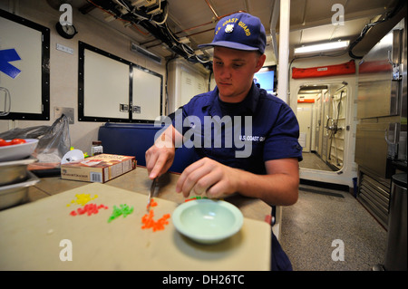 Matrose Nathan Gray, ein Crewmitglied an Bord der Coast Guard Cutter Beluga, schneidet sich Süßigkeiten für den Nachtisch Einstieg in einen Kochwettbewerb an Coast Guard Station Little Creek in Virginia Beach, VA., Montag, 28. Oktober 2013. Beteiligten Einheiten umfassen Küste Gu Stockfoto