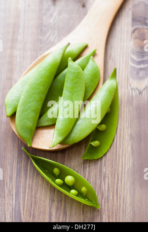 Erbsenschoten auf Löffel, hölzernen Hintergrund Stockfoto