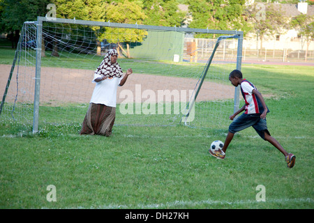 Die muslimische Frau (Mutter) in traditionellen Hijab dress spielen Fußball-Torwart für Teenager (Sohn). St Paul Minnesota MN USA Stockfoto