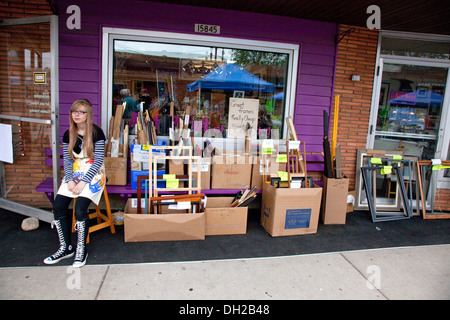 Junge Frau sitzt vor ihrem Rahmen-Shop Converse Chuck Taylor One Star high Tops tragen.  Hayward Wisconsin WI, USA Stockfoto