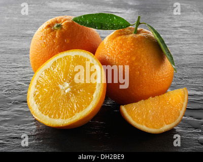Ganze und geschnittene frische Orangen mit Blättern