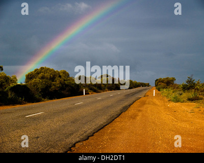Landstraße mit dunklen Wolken und Regenbogen, Western Australia Stockfoto
