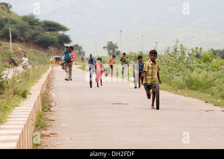 Indischen Jungen spielen mit Reifen auf einer Straße. Andhra Pradesh, Indien Stockfoto