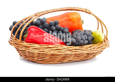 Die reifen Früchte der Trauben in einem Weidenkorb, Paprika rot und gelb. Auf weißem Hintergrund dargestellt. Stockfoto