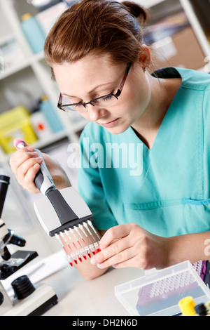 Frau analysiert den genetischen Code, Pipette und Mikroröhrchen für PCR-Reaktionen Stockfoto