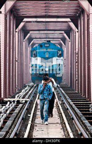Zwei Männer gehen auf die Bahn zu verfolgen, blind des nahenden Zug Stockfoto