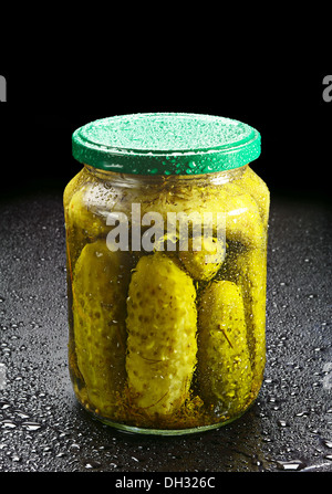 Gewürzgurken im Glas mit Wassertropfen auf schwarz Stockfoto