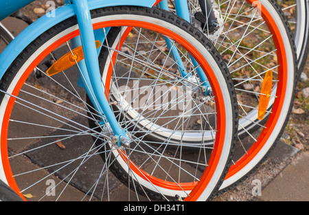 Bunte Fahrräder zu vermieten stehen in einer Reihe auf einem Parkplatz Stockfoto