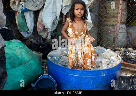 Ein junges Mädchen steht in einer Wanne zerkleinern Plastikwasserflaschen an einem recycling-Depot in Phnom Penh, Kambodscha. Stockfoto