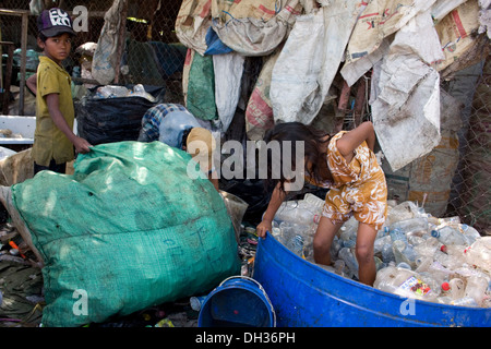 Ein junges Mädchen steht in einer Wanne zerkleinern Plastikwasserflaschen an einem recycling-Depot in Phnom Penh, Kambodscha. Stockfoto