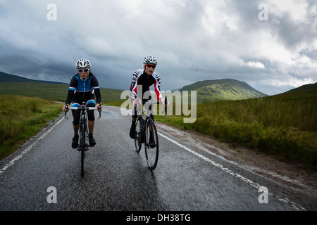 Paar der Radfahrer fahren einen nassen Pfad in die schottischen Highlands, Schottland, Vereinigtes Königreich Stockfoto