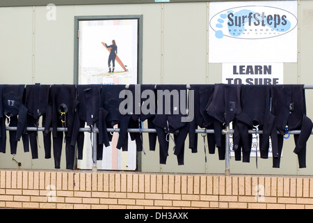 Neoprenanzüge, die Trocknung auf Geländer außerhalb einer Surf-Schule Stockfoto