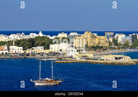 Hafeneinfahrt von Rhodos vor dem Casino und anderen Gebäuden, mit einem Segelschiff in den Vordergrund, Rhodos Stockfoto