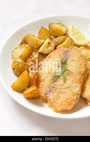 Paniertes Fischfilet mit gebackenen Kartoffeln auf weißen Teller Stockfoto