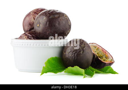 Frische Passionsfrucht mit grünen Blättern und weißen Keramikschale isoliert auf weißem Hintergrund Stockfoto