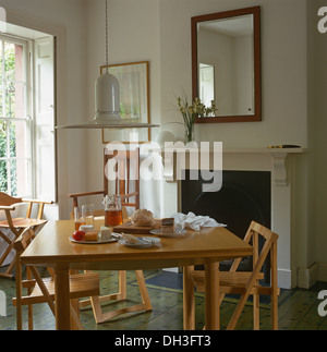 Pendelleuchte oben klappbar Holz Stühle einen einfachen Holztisch weiß Esszimmer für das Frühstück vor Kamin inmitten Stockfoto