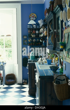 Blau lackierte Küche mit blassen blau geflieste Arbeitsplatten und schwarz + weiß Schachbrettmuster Vinylboden Stockfoto