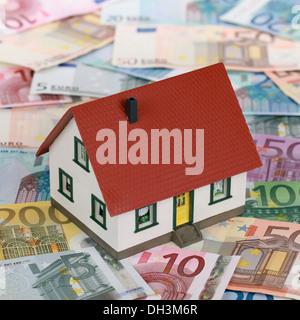 Symbolisches Bild eine Immobilienfinanzierung mit einem Haus auf Banknoten Stockfoto