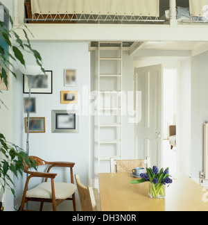 Vase mit Muscari auf hellen Holztisch in Wohnung Esszimmer mit Leiter zum Zwischengeschoss Schlafbereich Stockfoto