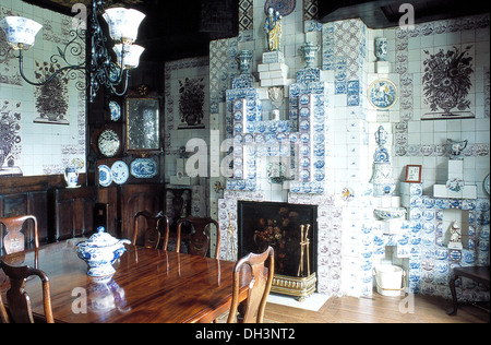 Blau + weiß Delft Stil geflieste Wände und Kamin im Speisesaal Land mit antiker Tisch und Stühle und Glas + Metall Kronleuchter Stockfoto