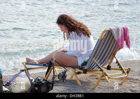 Frau sitzt in einem Liegestuhl am Ägäischen Meer. Griechenland, Insel Symi Stockfoto