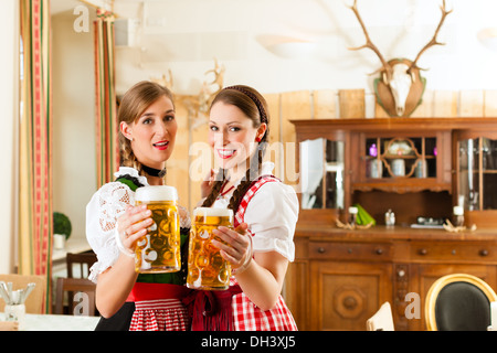 Zwei junge Frauen in traditionellen bayerischen Tracht im Restaurant oder Pub mit Bier und Bierkrug Stockfoto