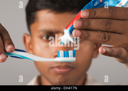 Junger Mann drückte Zahnpasta auf eine Zahnbürste Stockfoto