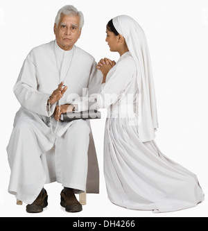 Nonne mit einem Priester ihre Sünden bekennen Stockfoto