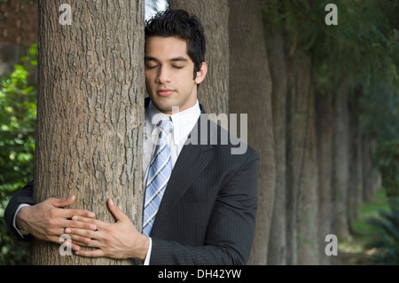 Geschäftsmann umarmt einen Baum Stockfoto