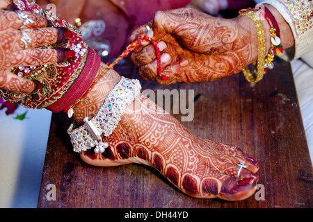 Bräutigam, die Füße der Braut im indischen Hochzeit Zeremonie Rajasthan Indien Faden entfernen Stockfoto