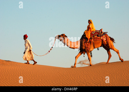 Mann von führenden Kamel in der Wüste mit Frauen sitzen auf Top Jaisalmer Rajasthan Indien Asien Herr # 784 Stockfoto