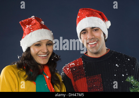 Porträt eines Paares Santa Hüte tragen und lächelnd Stockfoto