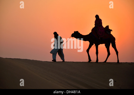 Mann führenden Kamel bei Sonnenuntergang in der Wüste Rajasthan Indien Asien Stockfoto