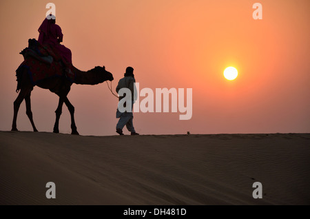 Mann führenden Kamel bei Sonnenuntergang in der Wüste Rajasthan Indien Asien Stockfoto