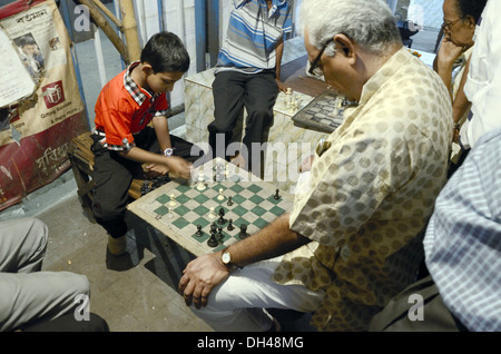 Junge spielt Schach mit Greis am Bürgersteig Fußweg Straßenrand Kolkata West Bengal Indien Stockfoto